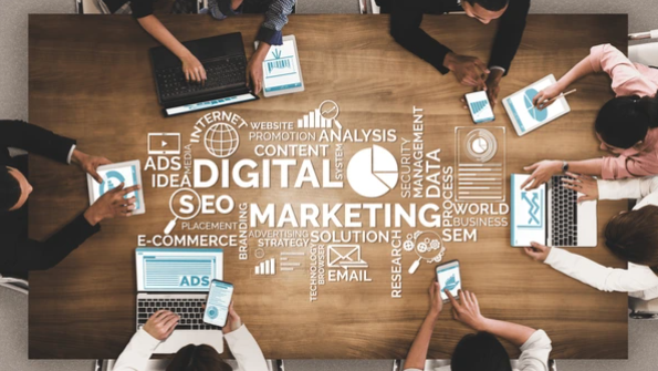 "Top view of a team working on laptops and tablets around a table with digital marketing and SEO strategy keywords overlay.