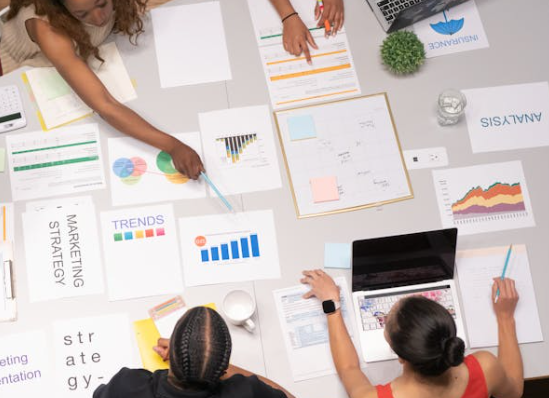 Top view of diverse marketing team analyzing keyword data, SEO charts, and eCommerce strategy documents during a planning session