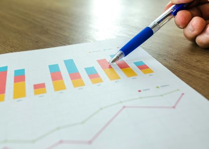 Hand pointing at colorful SEO analytics and growth charts on paper, representing search performance and digital strategy planning.