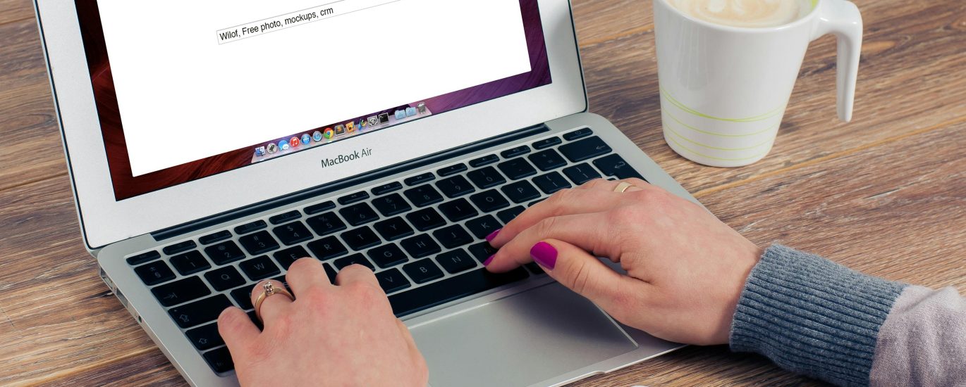Person using Google search on a laptop with smartphone and coffee on desk, representing local SEO and Google My Business optimization.
