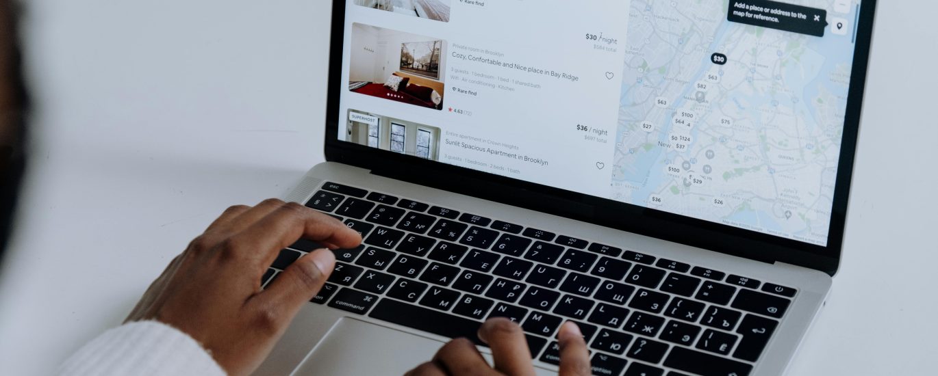 Hands typing on a laptop showing a map interface and local search results — illustrating local SEO and neighborhood-based search rankings.