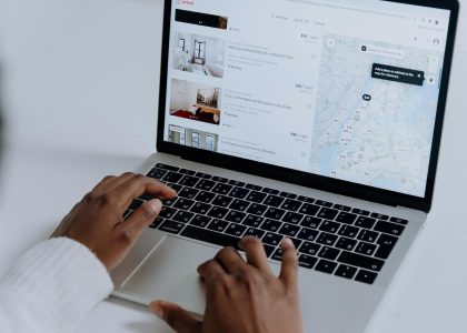 Hands typing on a laptop showing a map interface and local search results — illustrating local SEO and neighborhood-based search rankings.